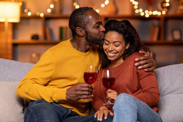 Cheers. Closeup of beautiful smiling young american couple drinking red wine, holding glasses and toasting, having romantic dinner, spending time together. Young black family celebrating
