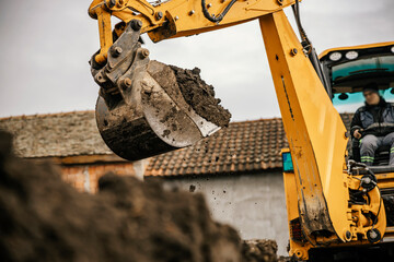An earth mover is removing soil from a pit on a reconstruction area. - obrazy, fototapety, plakaty