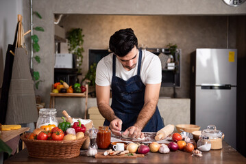 Handsome chef preparing meal in the kitchen. Caucasian man wearing aprons making pizza at home kitchen small business.