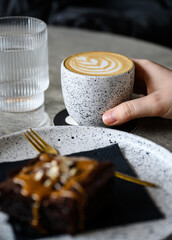 Hand holding a flat white on a table