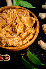 Peanut butter in a wooden plate on the table. 