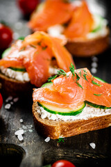 Sandwich with pieces of salmon on a cutting board. 