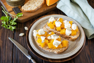 Healthy food, vegetarian appetizer on a rustic table. Open sandwiches whole grain ciabatta with spice pumpkin and feta cheese.