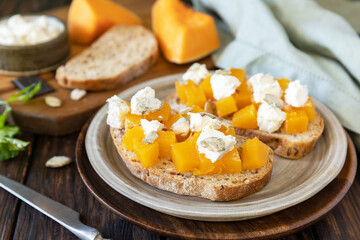 Healthy food, vegetarian appetizer on a rustic table. Open sandwiches whole grain ciabatta with spice pumpkin and feta cheese.