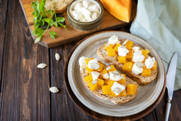 Healthy food, vegetarian appetizer on a rustic table. Open sandwiches whole grain ciabatta with spice pumpkin and feta cheese. Copy space.