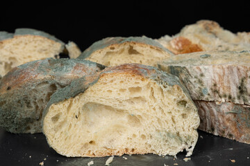 Mold on bread on a black background close-up. The danger of mold, stale products.