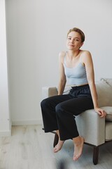 Teenage girl sitting on the couch at home smiling in home clothes and glasses with a short haircut, lifestyle without filters, free copy space