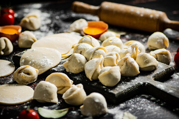 Raw dumplings on a cutting board with egg and flour. 