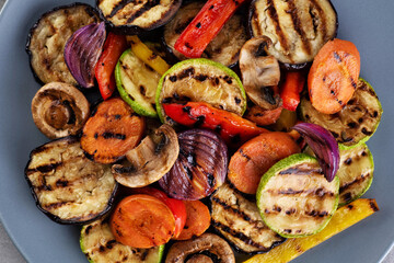 Grilled vegetables eggplants aubergine, carrots, zucchini, champignons, bell pepper, onion on a plate. Top view.