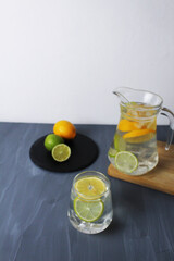 lemonade juice in glass drink from carbonated water and citrus fruits lemon lime and ice on a gray background with space for text copyspace