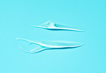 Liquid cosmetic gel smear, hyaluronic acid gel on a blue background with copy space.