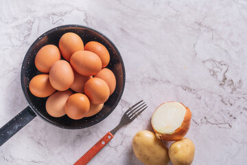 Huevos en una sarten listos para batir  con un tenedor y hacer tortilla de patatas y cebolla