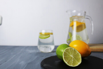 citrus fruits lemon and lime lie on a black tray and lemonade in a cubit glass. Preparation of drinks. Soft drinks