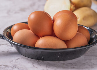 Huevos en una sarten listos para batir  con un tenedor y hacer tortilla de patatas y cebolla