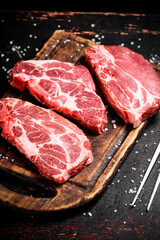 Raw pork steak on a wooden cutting board. 