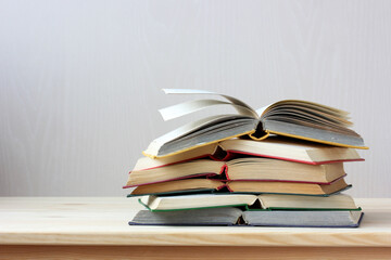 stack of open paper books in hard color covers on the table.