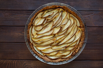 French pear pie on rustic wooden table, top view. 
