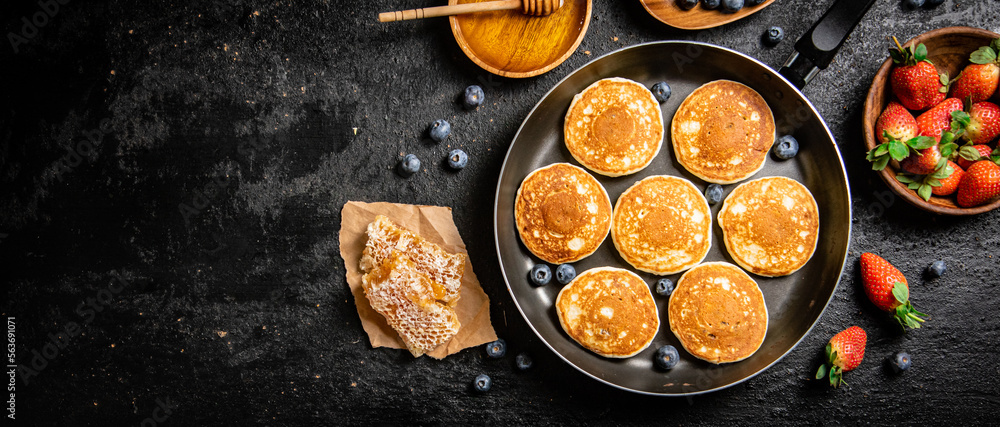 Wall mural Pancakes in a frying pan with fresh berries and honey. 