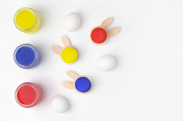 Multi-colored paint for eggs and eggs in a stand in the form of a rabbit on a light background