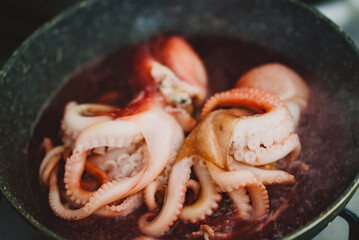 Cooking small octopuses in frying pan.