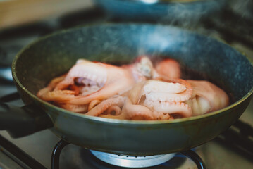 Cooking small octopuses in frying pan.