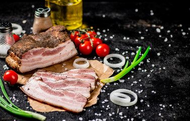 Pieces of lard on paper with onions and tomatoes. 