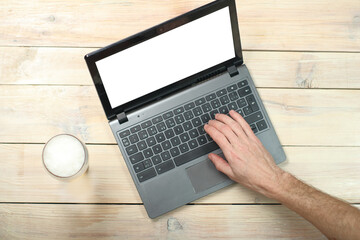 person typing on a laptop next to a beer mug