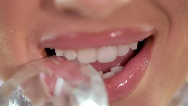 The girl demonstrates strong white teeth while biting a diamond