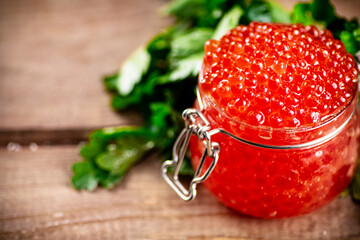 Red caviar in a glass jar with parsley. 