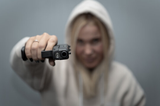 A girl with a gun in her hand, soft focus photo, main focus on the weapon.