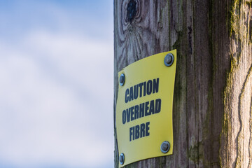 Sign on a wooden telephone pole warning of overhead [optical] fibre for rural broadband, County Down, Northern Ireland, United Kingdom, UK