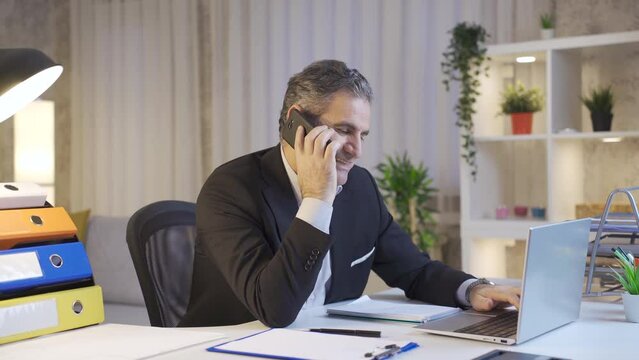 Happy mature businessman working on laptop while talking by phone.
Business connector, marketer mature businessman making phone call and using laptop.
