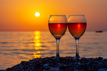 Two glasses of wine on a beach at sunset