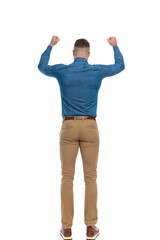 back view of casual young man holding fists up and celebrating victory