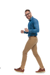 Fototapeta premium side view of excited guy with glasses celebrating victory and walking