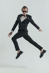 elegant man in tuxedo jumping in the air in a dynamic way and posing