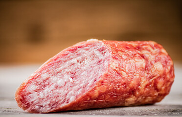 A piece of salami sausage on the table. 