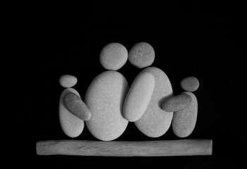 Pebble family. embracing Family shaped sign. Stone family sitting together . Happy family parents with their children built out of rocks. isolated on black background.