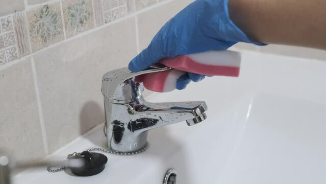 4k v&iacute;deo de se&ntilde;ora de la limpieza lavando grifo del cuarto de ba&ntilde;o con un estropajo y guantes
