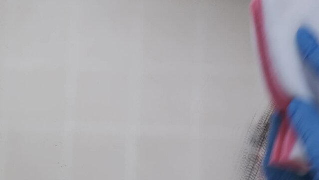 4k v&iacute;deo. Mujer de la limpieza trabajadora concentrada limpiando los cristales del cuarto de ba&ntilde;o 