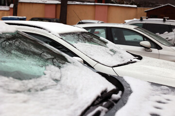 Samochód zaparkowany zimą na parkingu z oszronioną szybą.