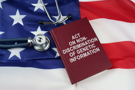 On the US flag lies a stethoscope and a book with the inscription - ACT ON NON-DISCRIMINATION OF GENETIC INFORMATION