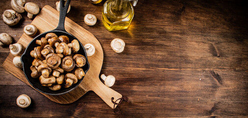 Fried mushrooms in a frying pan on a cutting board. 