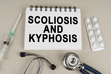 On a gray surface there is a syringe, a stethoscope and a notepad with the inscription - scoliosis...