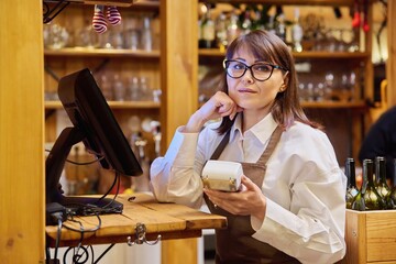 Woman worker manager of restaurant holding wireless banuov payment terminal