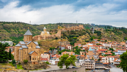 Fototapeta premium Tbilisi old town with Metekhi church, Narikala Fortress on hill and sulfur baths district. Tiflis with ancient architecture is popular tourist destination in Georgia