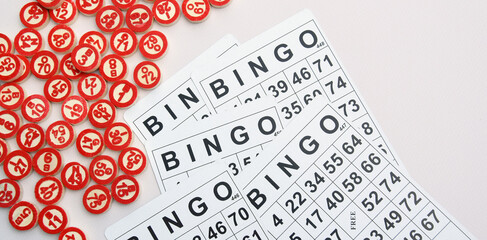 Many wooden chips with numbers and cards for a board game of bingo or lotto on a light background.