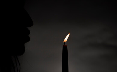 Silhouette of male with light of candle with dark background