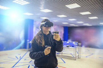Man playing with VR set holding controllers in hands in VR club