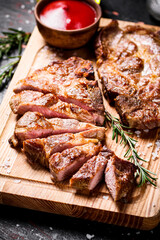 Slices of grilled steak pork on a wooden cutting board. 